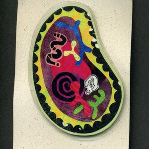 May include: A colorful sticker with a paisley-like design. The sticker features a swirl pattern in black, purple, and red, with a yellow and green abstract design. The sticker has a black border with a yellow starburst around the edge.