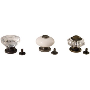 May include: Three cabinet knobs with screws. One is clear crystal, one is white ceramic, and one is clear crystal with a brass base.