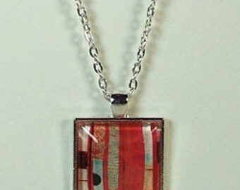 May include: A square pendant necklace with a red, white, and black patterned glass tile. The tile is set in a silver frame and hangs from a silver chain.
