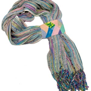 May include: A colorful scarf with a patchwork design. The scarf features a mix of pastel colors, including blue, pink, and green, with a fringed edge. The scarf is wrapped around itself, showcasing its texture and design.