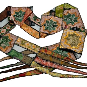 May include: A long, multi-colored fabric ribbon with a patchwork design. The ribbon is made of different fabrics, including silk, velvet, and lace. The ribbon is decorated with gold embroidery and has a fringe on the ends.