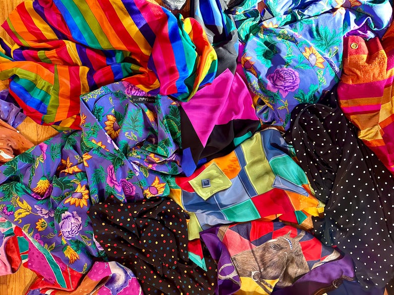 May include: A colorful assortment of fabric scraps in various patterns, including stripes, polka dots, and floral designs. The fabrics are in shades of blue, green, pink, yellow, and orange.