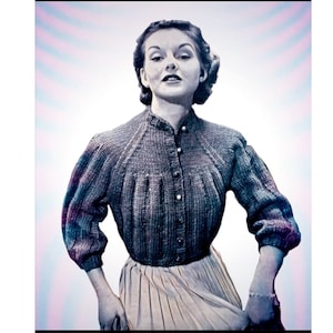 May include: A woman wearing a gray knitted sweater with a button-up front and a white skirt. The sweater has a textured pattern and the skirt is pleated.