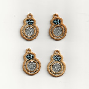 Puede incluir: Cuatro dijes de anillo de color dorado con un diamante azul en el centro. Los dijes tienen un diseño de malla plateada y son perfectos para agregar un toque de brillo a tus proyectos de joyería.