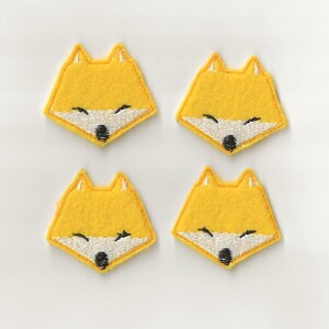 May include: Four yellow felt fox face appliques with white embroidered eyes and a black embroidered nose.