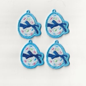 Puede incluir: Cuatro parches bordados en forma de huevo de Pascua azul y blanco con una cinta azul y espolvoreados de colores.