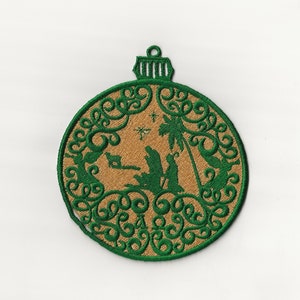 May include: Embroidered Christmas bauble with a green filigree design. The bauble features a tan centre with a green silhouette of the nativity scene, including Mary, Joseph, and baby Jesus, along with a star and palm tree.