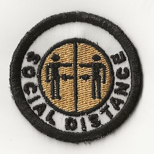 Puede incluir: Un parche circular bordado blanco y negro con las palabras "Social Distance" alrededor del borde. Dos figuras de palo están en el centro, frente a frente con una línea entre ellas.