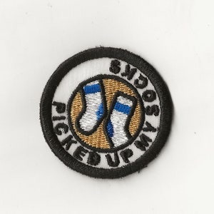 May include: A white embroidered patch with a black border. The patch features a pair of socks in a circle with the text "Picked Up My Socks".