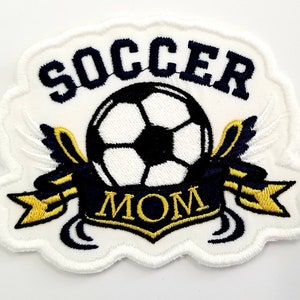 May include: White embroidered patch with a football, wings, and a banner that reads "Soccer Mom".
