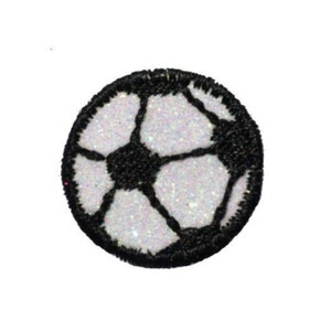 Puede incluir: Un parche de fútbol blanco y negro con purpurina. El parche es redondo y tiene un contorno negro.