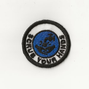 May include: A white and black circular embroidered patch with a blue circle in the center. The blue circle has a black silhouette of two hands washing with soap and water. The text "Scrub Your Hands" is written in a white circle around the blue circle.