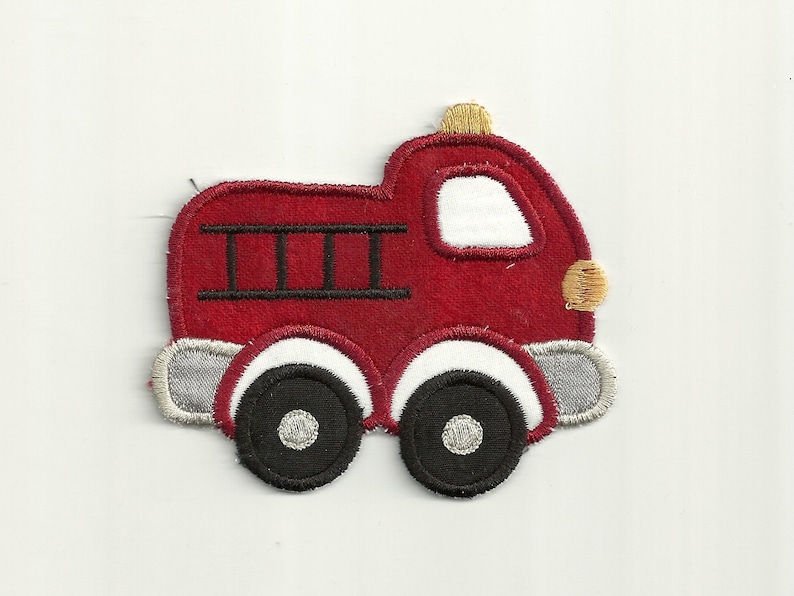 Peut inclure: Applique de camion de pompiers en feutrine rouge avec une &eacute;chelle noire, des roues blanches et des d&eacute;tails jaunes.