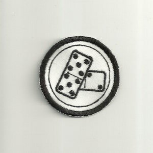 May include: A black and white embroidered patch with a circle border. The patch features two dominoes, one with five dots and the other with one dot.