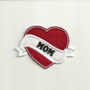 May include: Red felt heart with a white embroidered banner that says "MOM" in black lettering.