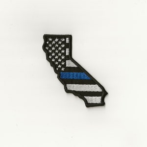 May include: An embroidered patch in the shape of the state of California with an American flag design and a blue line running through the middle.