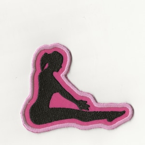 May include: A pink and black embroidered patch featuring a silhouette of a person sitting in a yoga pose.