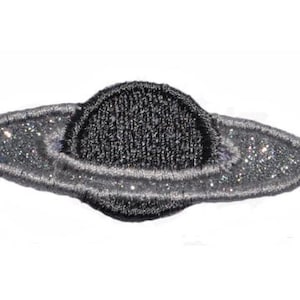 May include: A black and silver embroidered iron-on patch of a planet with rings.