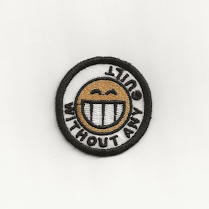 May include: A round, black and white embroidered patch with a smiling yellow face and the text "Guilty Without Any".