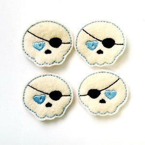 May include: Four white felt skull patches with blue embroidered hearts for eyes and black embroidered eyepatches.