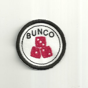 May include: A white circular patch with a black border. The center of the patch has a red embroidered image of three dice stacked on top of each other. The word "BUNCO" is embroidered in black above the dice.