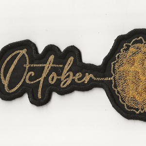 以下が含まれることがあります： 黒い刺繍パッチに、金糸で「10月」と刺繍され、金色の刺繍の円が施されています