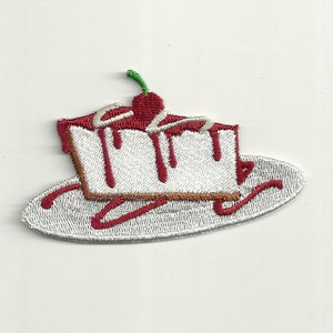 May include: Embroidered iron-on patch of a white cheesecake slice with red cherry and sauce on a white plate.