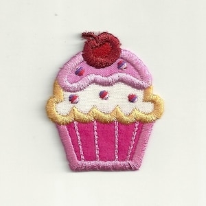Puede incluir: Cupcake rosa y blanco con una cereza roja en la parte superior. El cupcake tiene un glaseado amarillo y chispas.