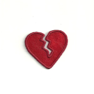 May include: A red felt heart patch with a white crack down the middle, symbolizing a broken heart.