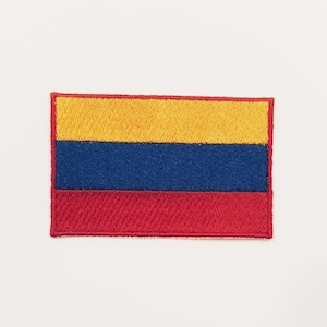 May include: An embroidered patch featuring the flag of Colombia. The flag is yellow, blue, and red with three horizontal stripes.
