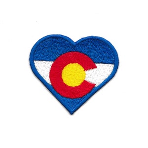 May include: A heart-shaped patch with the Colorado state flag. The flag features a blue field with a large gold circle in the center, surrounded by a red ring. The circle has a white 'C' inside. The flag is bordered by a white stripe and a blue stripe.