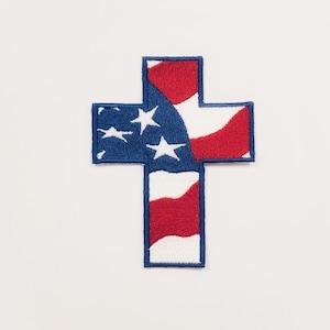 Op de afbeelding: Een geborduurde patch in de vorm van een kruis met het ontwerp van de Amerikaanse vlag, in blauw en rood.