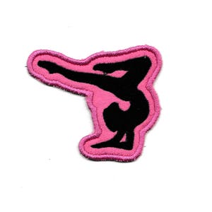 Könnte beinhalten: Rosa Stoff-Patch mit einer schwarzen Silhouette einer Turnerin, die einen Handstand macht.