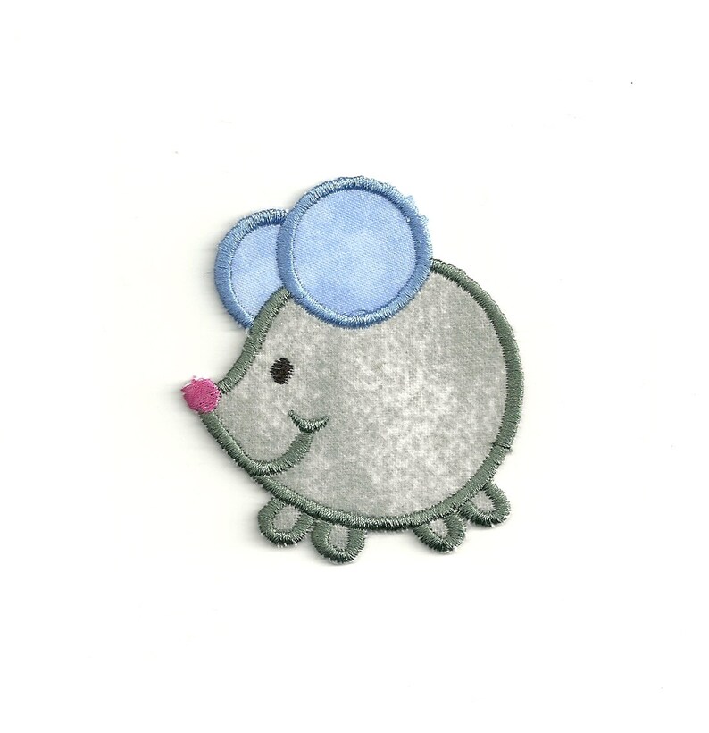 May include: A gray mouse with blue ears and a pink nose. The mouse is embroidered and has a simple, cartoon-like design.