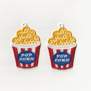 以下が含まれることがあります： 黄色のポップコーンと青い「POP CORN」の文字が入った、赤と白のストライプのポップコーン容器が2つです。