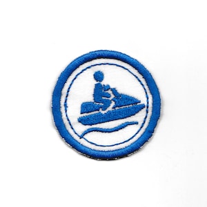 Peut inclure: Un écusson brodé bleu et blanc avec une silhouette blanche d'une personne conduisant un jet ski sur une vague.