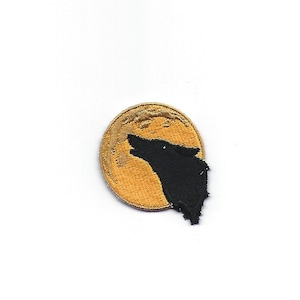 May include: A gold embroidered patch with a black silhouette of a wolf howling at the moon.