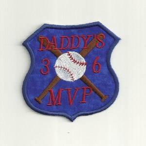 Op de afbeelding: Blauwe viltpatch met een witte honkbal, twee gekruiste bruine knuppels en de tekst "DADDY'S 3 6 MVP" in rode borduurwerk.
