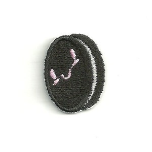 May include: Black embroidered patch with a white border and a pink floral design. The patch is oval-shaped and has a textured appearance. The design is a stylized floral element.