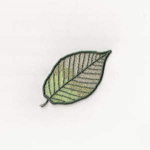 May include: A green embroidered leaf with a light green and white center.