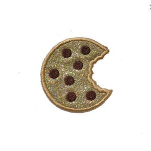 May include: A brown chocolate chip cookie with a bite taken out of it. The cookie is decorated with a sparkly gold finish.