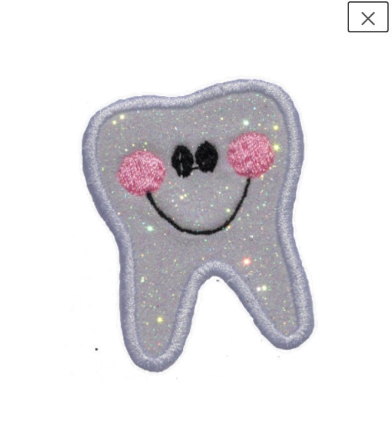 K&ouml;nnte beinhalten: Ein wei&szlig;er, glitzernder Zahn mit einem l&auml;chelnden Gesicht und rosa Wangen. Der Zahn ist mit schwarzem Faden gestickt.