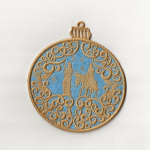 May include: Embroidered Christmas bauble with a light blue centre featuring a gold silhouette of a religious scene. The bauble has a gold filigree border and a loop for hanging. The design is reminiscent of a traditional Christmas decoration.