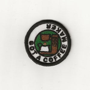 May include: A round, black and white embroidered patch with the text "Gotta Coffee Maker" and a cartoon image of a coffee maker.