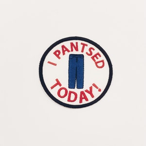 May include: A round, white patch with a black outline. The patch has red text that says "I Pantsed Today!" with a blue pair of pants in the center.