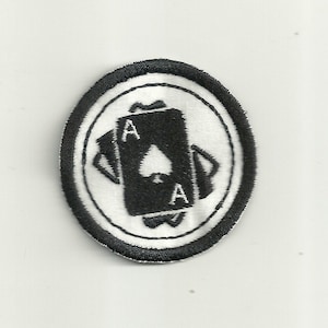 Könnte beinhalten: Schwarz-weiß gestickter Aufnäher mit zwei Asen von Pik in einem Kreis.