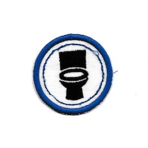May include: Round patch with a white center featuring a black toilet graphic. The patch is encircled by a blue border with a stitched design. The patch is likely an embroidered or sewn-on emblem.