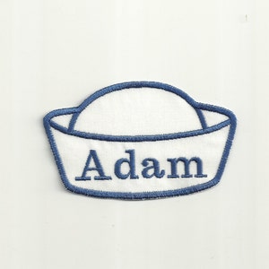 May include: Blue and white embroidered sailor hat patch with the name "Adam" in white.