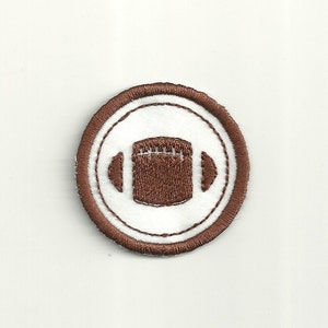 May include: Brown embroidered iron-on patch with a white circle and a brown football in the center.
