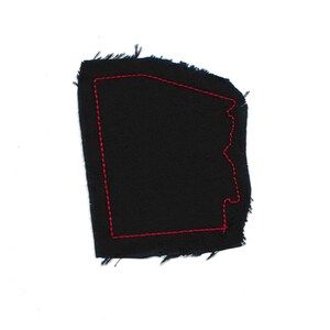 May include: A black fabric patch with a red stitched outline in the shape of a state.